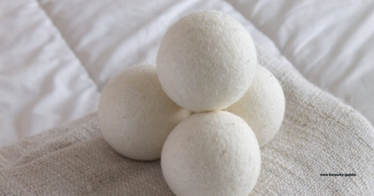 Four white wool balls for cruelty-free dryer sheets on a bed.